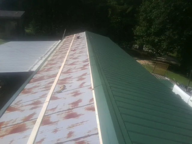 Old rusted panels beside newly installed green metal roofing — Wind Damage Roof Repair by Roofing Brothers in Allensville